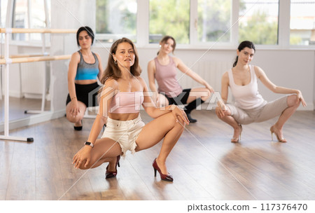Dynamic female dancers rehearsal, performing sensual choreography in high heels, epitomizing grace in studio 117376470