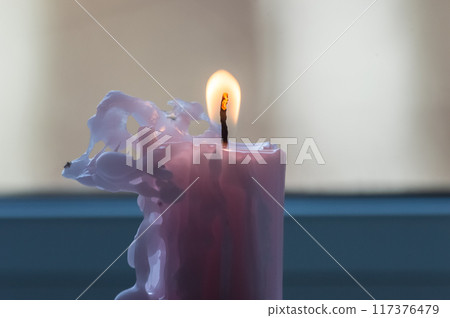 Close up of a burning candle in a glass vase on the windowsill Close up of a burning candle in a glass vase on the windowsill 117376479