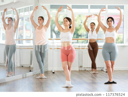 Young girl practicing ballet positions standing in row with others 117376524