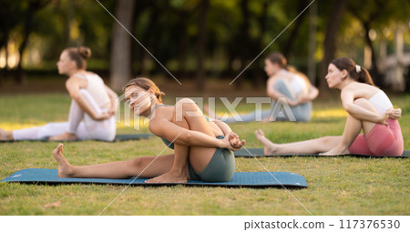 Yoga lesson visitors girls perform Mariciasana in park 117376530