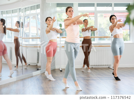 Young girl practicing basic ballet movements at group class 117376542
