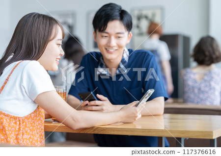 年輕人在咖啡館裡看智能手機 年輕人在咖啡館裡看智能手機 117376616