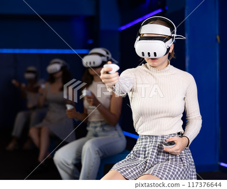 Young woman immersed in virtual reality game in gaming center Young woman immersed in virtual reality game in gaming center 117376644