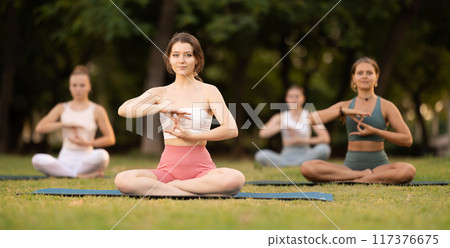Lotus pose - young pretty girls doing yoga outdoors Lotus pose - young pretty girls doing yoga outdoors 117376675