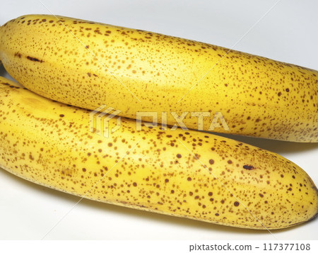 A fully ripe banana with black spots on its surface 117377108