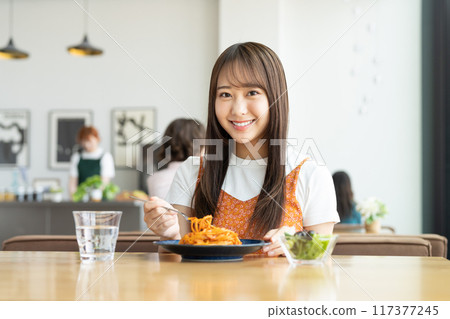 Young woman eating pasta in a cafe Young woman eating pasta in a cafe 117377245
