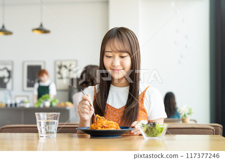 Young woman eating pasta in a cafe Young woman eating pasta in a cafe 117377246