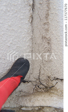 Close-up of a worker inspecting the deterioration of exterior wall joints 117377670