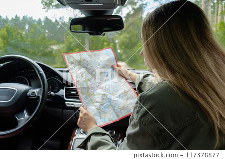 Blonde woman sitting inside the car checking the route on map to get to the destination. Afraid to get lost in forest. Young tourist explore local travel making candid real moments. True emotions Blonde woman sitting inside the car checking the route on map to get to the destination. Afraid to get lost in forest. Young tourist explore local travel making candid real moments. True emotions 117378877