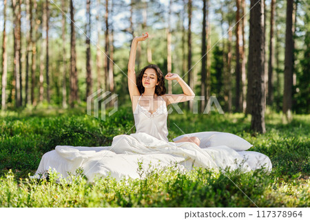 Girl wakes up in a summer forest Girl wakes up in a summer forest 117378964