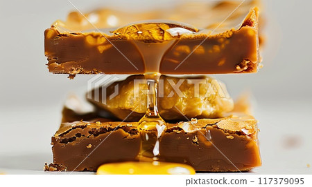 Close-up of rich chocolate brownies layered with caramel, showcasing a gooey center and topped with chocolate pieces, perfect for a decadent treat.. 117379095