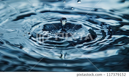 Close-up of a water droplet hitting the surface, creating ripples in the calm water, capturing a moment of fluid motion... 117379152