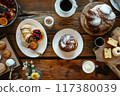 Gourmet breakfast scene featuring a beautifully crafted pastry, a cup of coffee, fresh berries, and a cinnamon drink.. 117380039