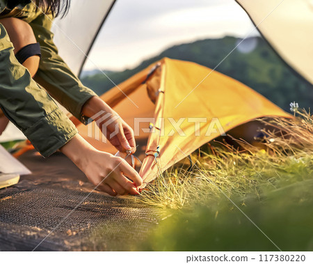 Image of a woman setting up a tent 117380220