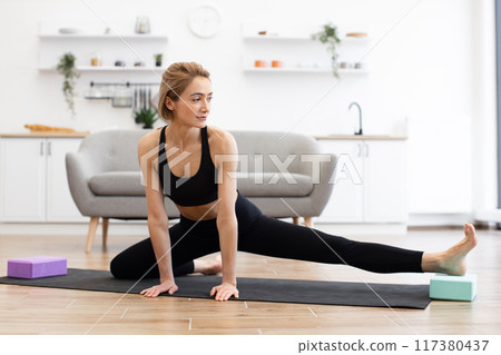 Woman practicing yoga at home in bright modern living room 117380437