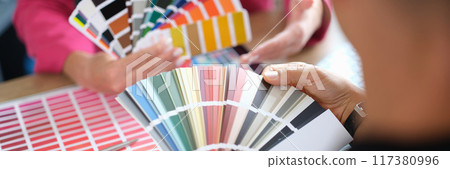 Woman designer holding fan of colourful paper samples in hand. 117380996