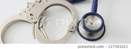 Metal handcuffs and stethoscope on white background 117381021