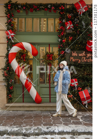 woman walking by city street decorated for christmas woman walking by city street decorated for christmas 117381178