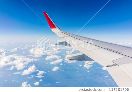 View from the airplane window at a beautiful cloudy sky and the airplane wing 117381706