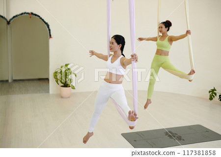 Practicing Aerial Yoga on Suspended Ribbons in Studio 117381858