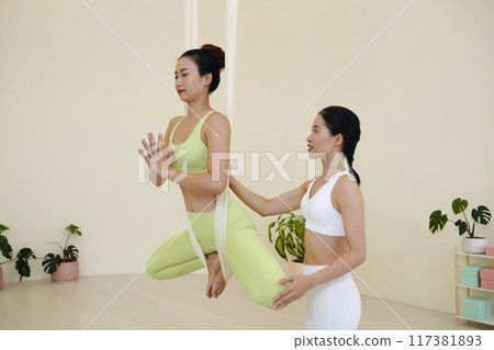 Executing Aerial Yoga Poses with Trainer Guidance Executing Aerial Yoga Poses with Trainer Guidance 117381893