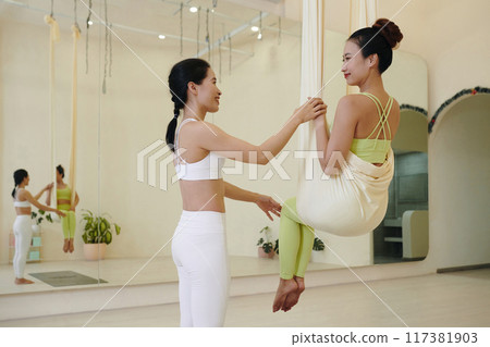 Practicing Aerial Yoga Poses in Bright Studio 117381903
