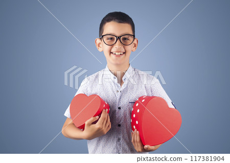 cute boy with gifts for a party. studio photo on the blue background 117381904