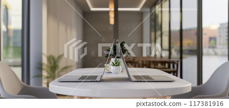 Two laptop computers on a modern white table in a contemporary meeting room or co-working space. Two laptop computers on a modern white table in a contemporary meeting room or co-working space. 117381916