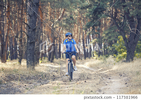 woman cyclist rides in the pine forest on a mountain bike. 117381966