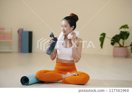 Woman Resting After Yoga Session Holding Water Bottle 117381968