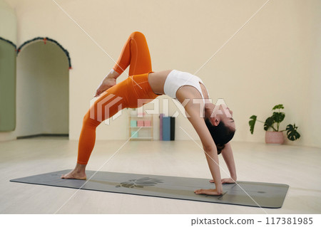 Practicing Advanced Yoga Pose in Modern Studio Setting Practicing Advanced Yoga Pose in Modern Studio Setting 117381985