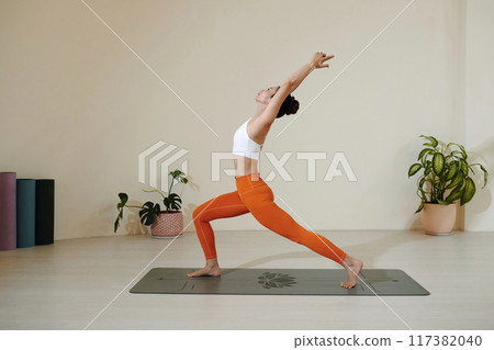Practicing Yoga in Minimalist Studio for Mindfulness 117382040