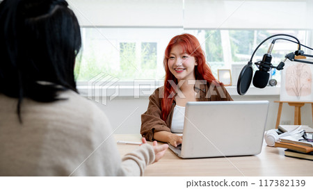 A beautiful and friendly Asian female radio host or podcaster is interviewing a guest in her studio. A beautiful and friendly Asian female radio host or podcaster is interviewing a guest in her studio. 117382139
