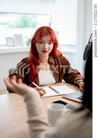 A beautiful Asian female podcaster is interviewing a guest, listening to their answers. A beautiful Asian female podcaster is interviewing a guest, listening to their answers. 117382230