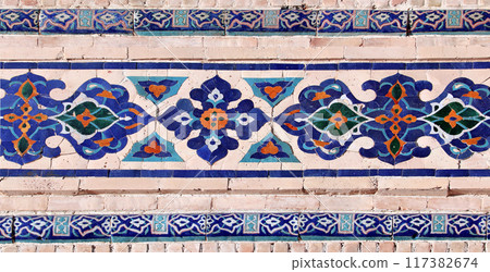 Horizontal background with detail of ancient mosaic walls with clay details and geometric ceramic tile ornament. Traditional iranian tile decorations Horizontal background with detail of ancient mosaic walls with clay details and geometric ceramic tile ornament. Traditional iranian tile decorations 117382674