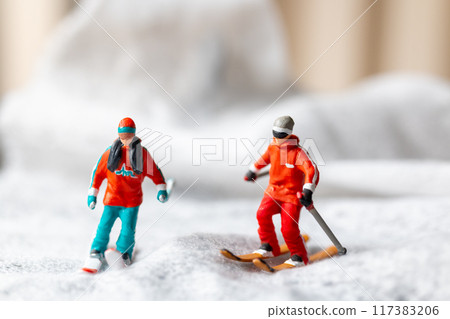 Miniature figurine of a skier in motion skiing across a white snowy landscape 117383206
