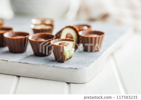 Sweet pralines. Chocolate truffles on cutting board on white table. 117383235