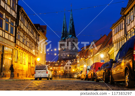 Charming Quedlinburg town evening street view illuminated with Christmas lights old St. Nicholas Church St. Nicholas Kirche background historical half-timbered houses facade. Festive city German 117383297