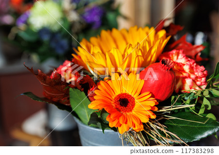 Vibrant Autumn Flower Bouquet in Rustic Metal Vase on wooden table at countryside village farm rustical house. Bright floral seasonal composition in bucket. Nature farmyard blossom arrangement Vibrant Autumn Flower Bouquet in Rustic Metal Vase on wooden table at countryside village farm rustical house. Bright floral seasonal composition in bucket. Nature farmyard blossom arrangement 117383298