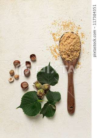 wooden spoon with hazelnut flour, top view, no people, on a white table 117384351