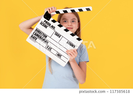 Little child girl wear blue t-shirt holding clapperboard isolated on yellow background. Children lifestyle childhood concept. 117385618