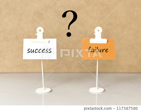 Two paper clips and a white and orange piece of paper with the words success and failure and a question mark 117387580