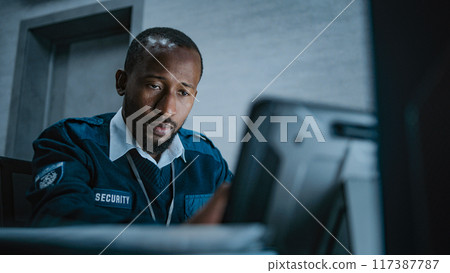 African American male security operator uses tablet computer sitting in monitoring center African American male security operator uses tablet computer sitting in monitoring center 117387787