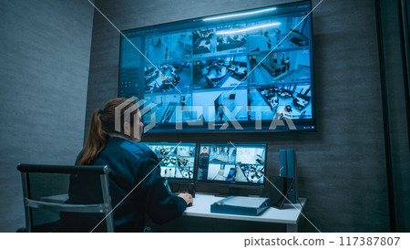 Female CCTV operator controls surveillance cameras using computer 117387807