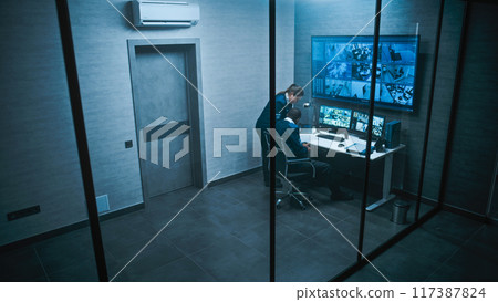 African American CCTV operator works on computer watching security cameras African American CCTV operator works on computer watching security cameras 117387824