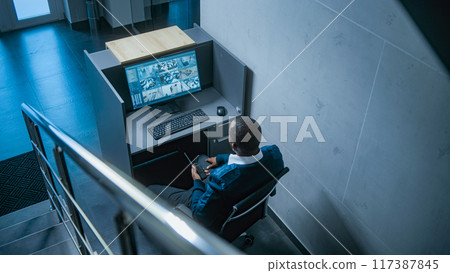 African American male security guard sits at the workplace with PC, talks to female colleague 117387845