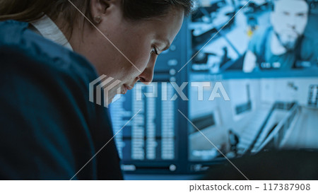 Multiethnic surveillance operators control security cameras on screens in monitoring center 117387908