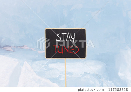 Stay tuned symbol. Concept words Stay tuned on beautiful yellow black blackboard. Beautiful blue ice background. Business, support, motivation, psychological and stay tuned concept. Copy space. 117388828