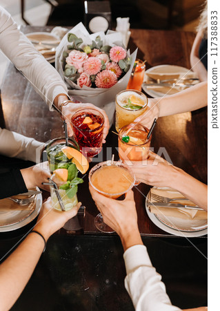 Friends toasting with colorful cocktails at a dinner party, celebrating special moments together Friends toasting with colorful cocktails at a dinner party, celebrating special moments together 117388833