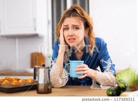 Sleepy woman drinking fresh coffee in morning Sleepy woman drinking fresh coffee in morning 117389311